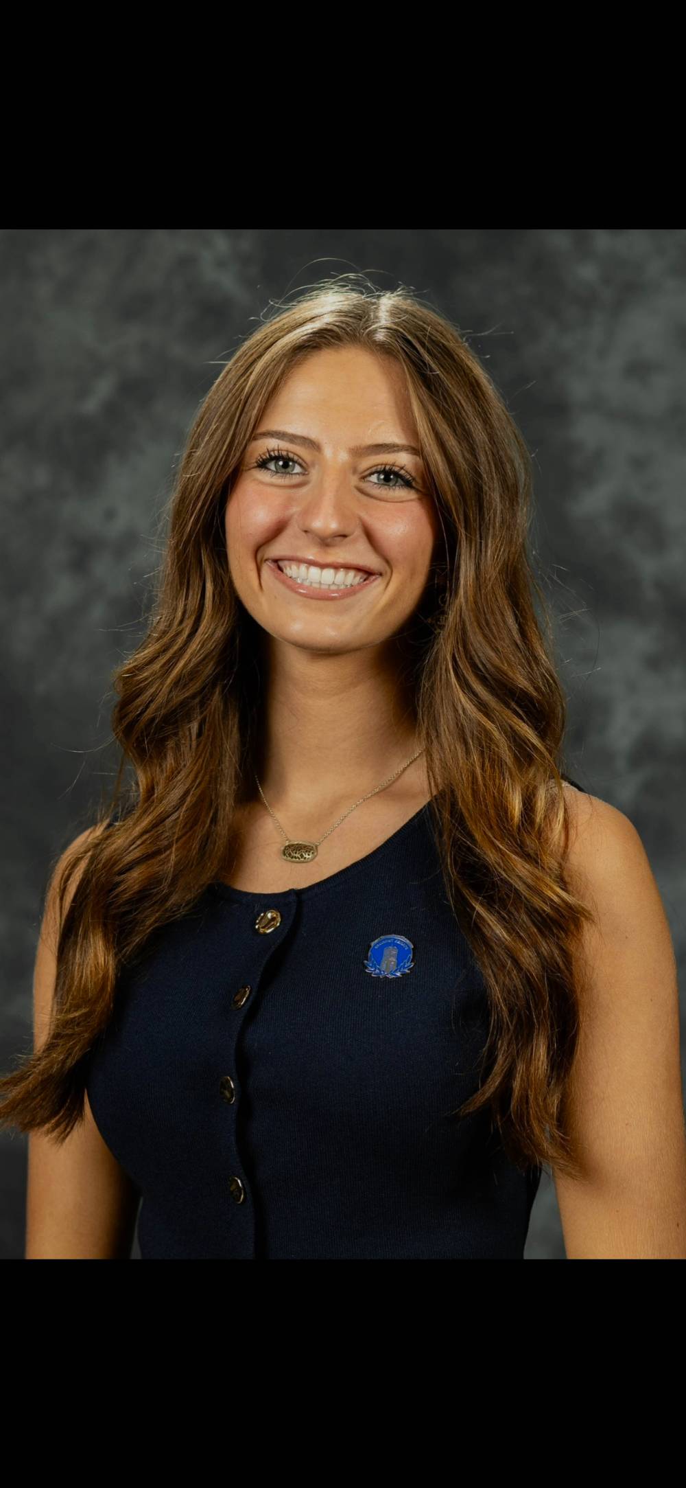 Image 1 of 2 Person smiling in front of dark background